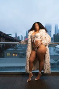a woman in a fur coat posing on a balcony